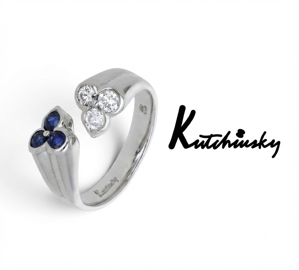 A mid-century 18ct white gold crossover ring features opposing trefoil terminals set with blue sapphires and brilliant-cut diamonds. View II