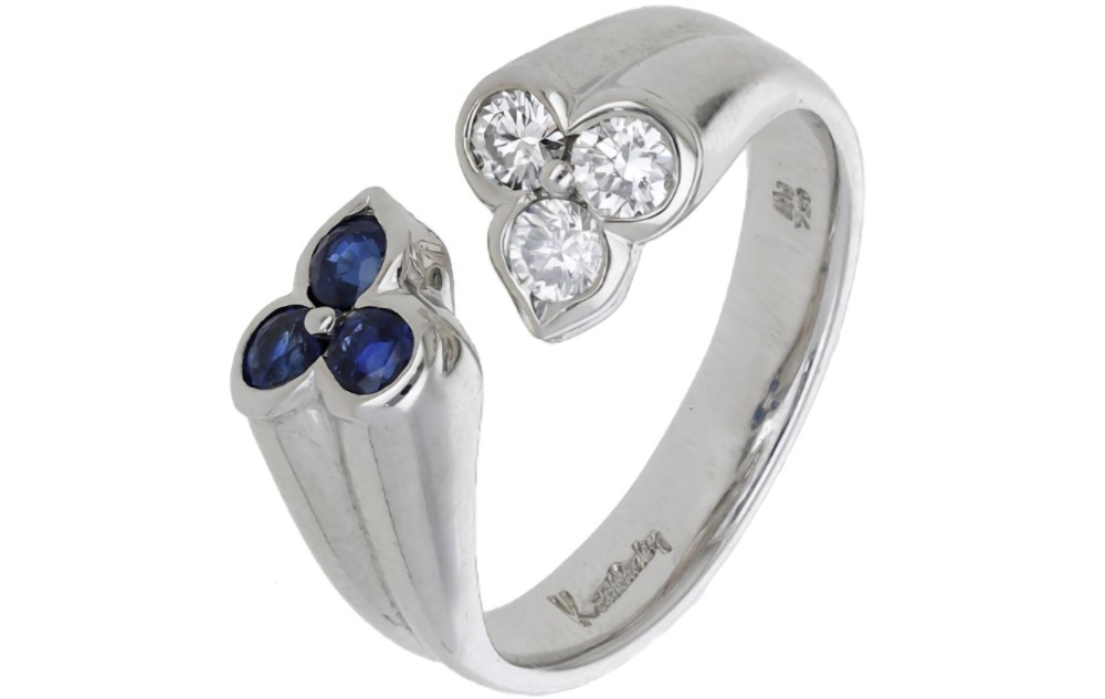 A mid-century 18ct white gold crossover ring features opposing trefoil terminals set with blue sapphires and brilliant-cut diamonds. View VIII