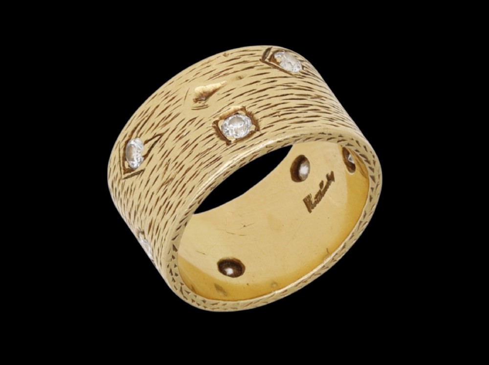 A wide 18ct yellow gold band ring featuring a textured bark-like surface set with brilliant-cut diamonds and stamped with London hallmarks inside. View V