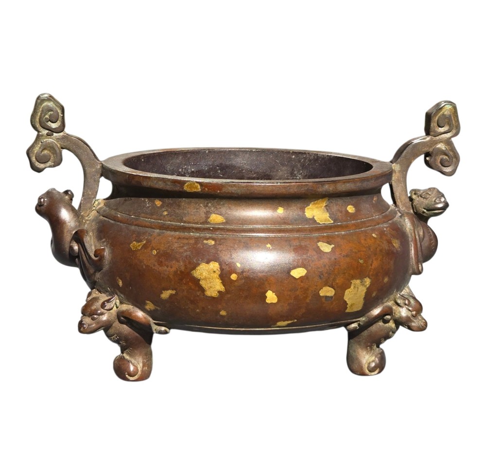 An 18th-century Chinese gilt-splashed bronze tripod censer featuring scroll handles, animal-mask legs, a dark hardwood cover topped with a carved jade finial, and a fitted bronze stand. View VIII