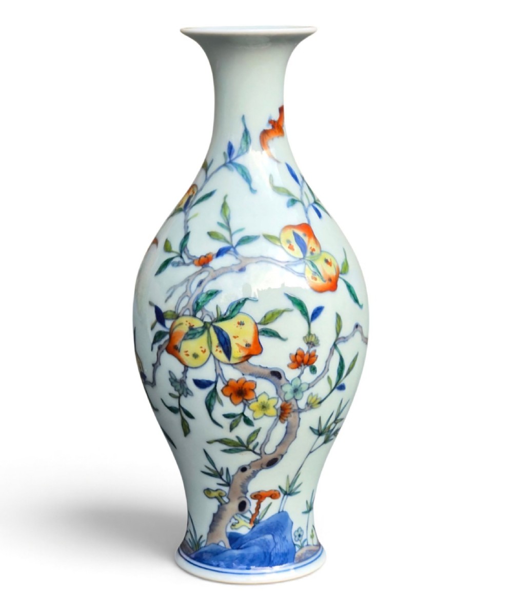 A Chinese porcelain garlic-head vase decorated with hand-painted peaches, orange bats, green leaves, and blue rockwork on a white background.