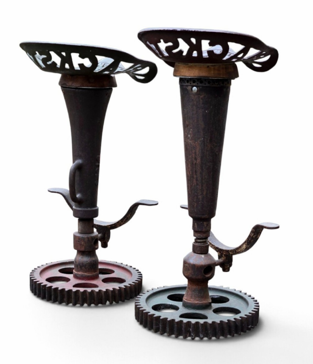 A pair of heavy industrial bar stools constructed with embossed Blackstone and Company cast-iron tractor seats, central metal columns with integrated footrests, and heavy gear cog bases. View II