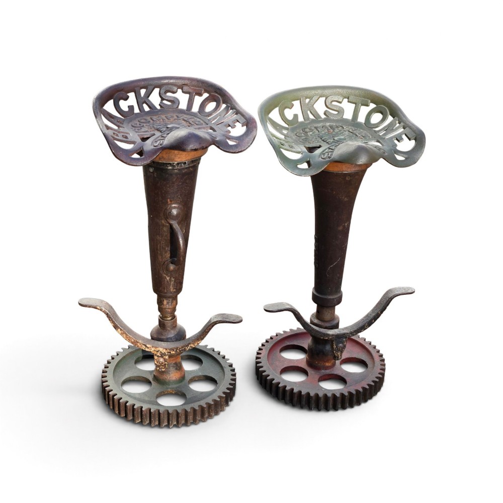 A pair of heavy industrial bar stools constructed with embossed Blackstone and Company cast-iron tractor seats, central metal columns with integrated footrests, and heavy gear cog bases. View VIII