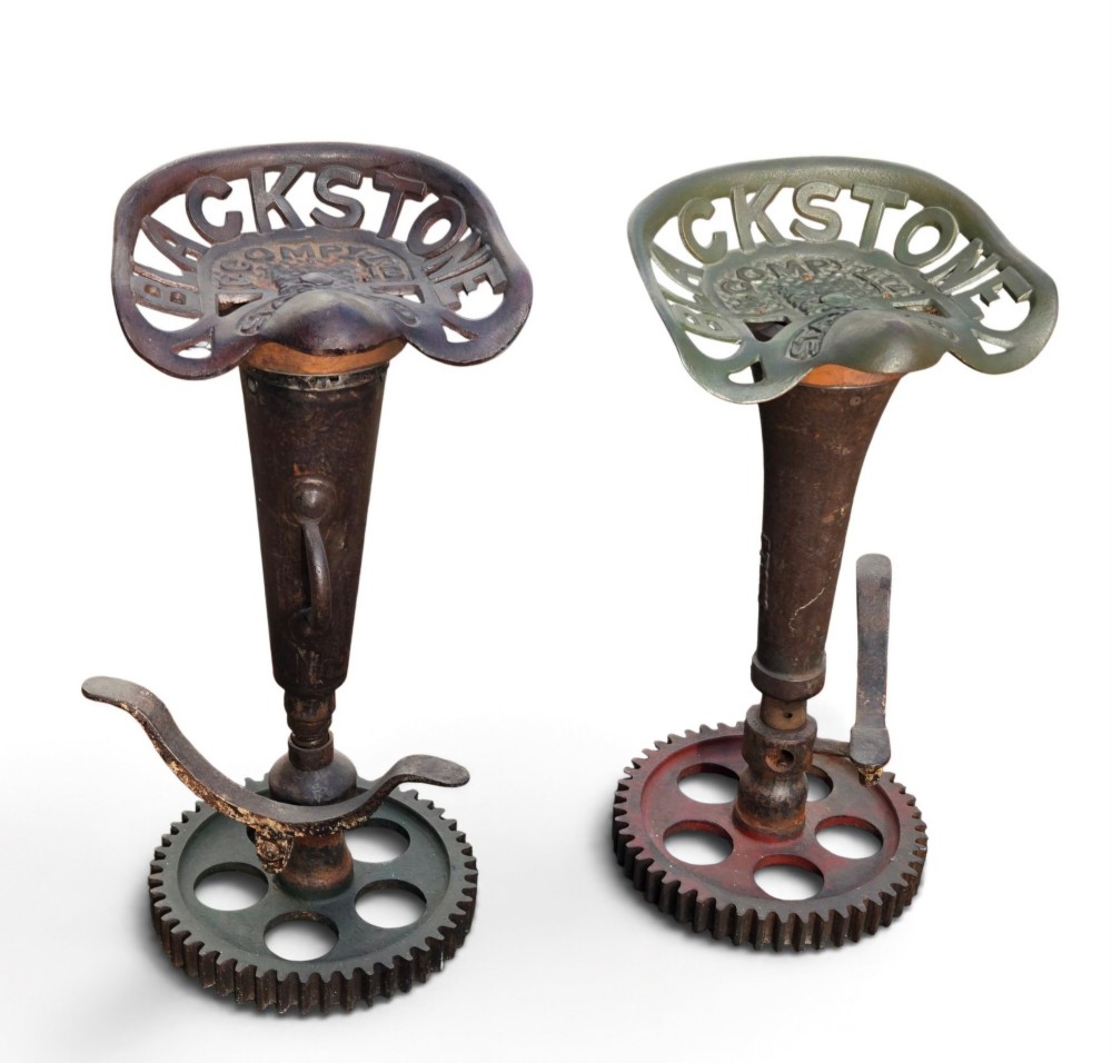 A pair of heavy industrial bar stools constructed with embossed Blackstone and Company cast-iron tractor seats, central metal columns with integrated footrests, and heavy gear cog bases. View XIV