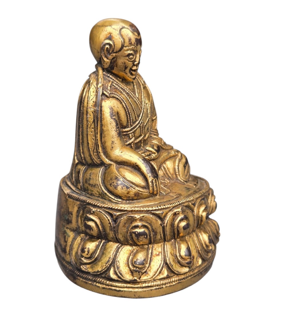 An 18th-century gilt-bronze miniature figure of Lama Shang seated cross-legged on a double-lotus pedestal in patterned robes. View III