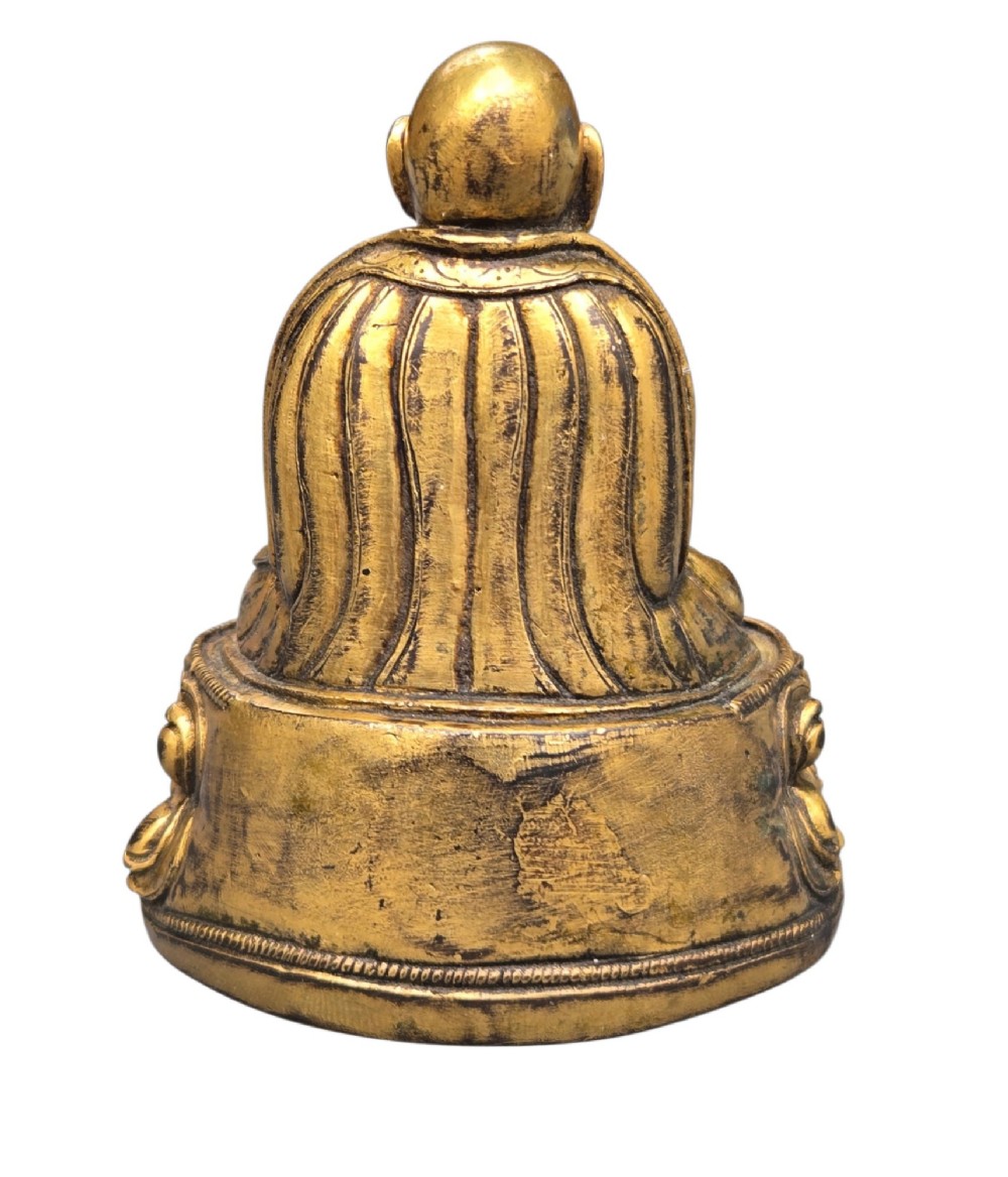 An 18th-century gilt-bronze miniature figure of Lama Shang seated cross-legged on a double-lotus pedestal in patterned robes. View IV