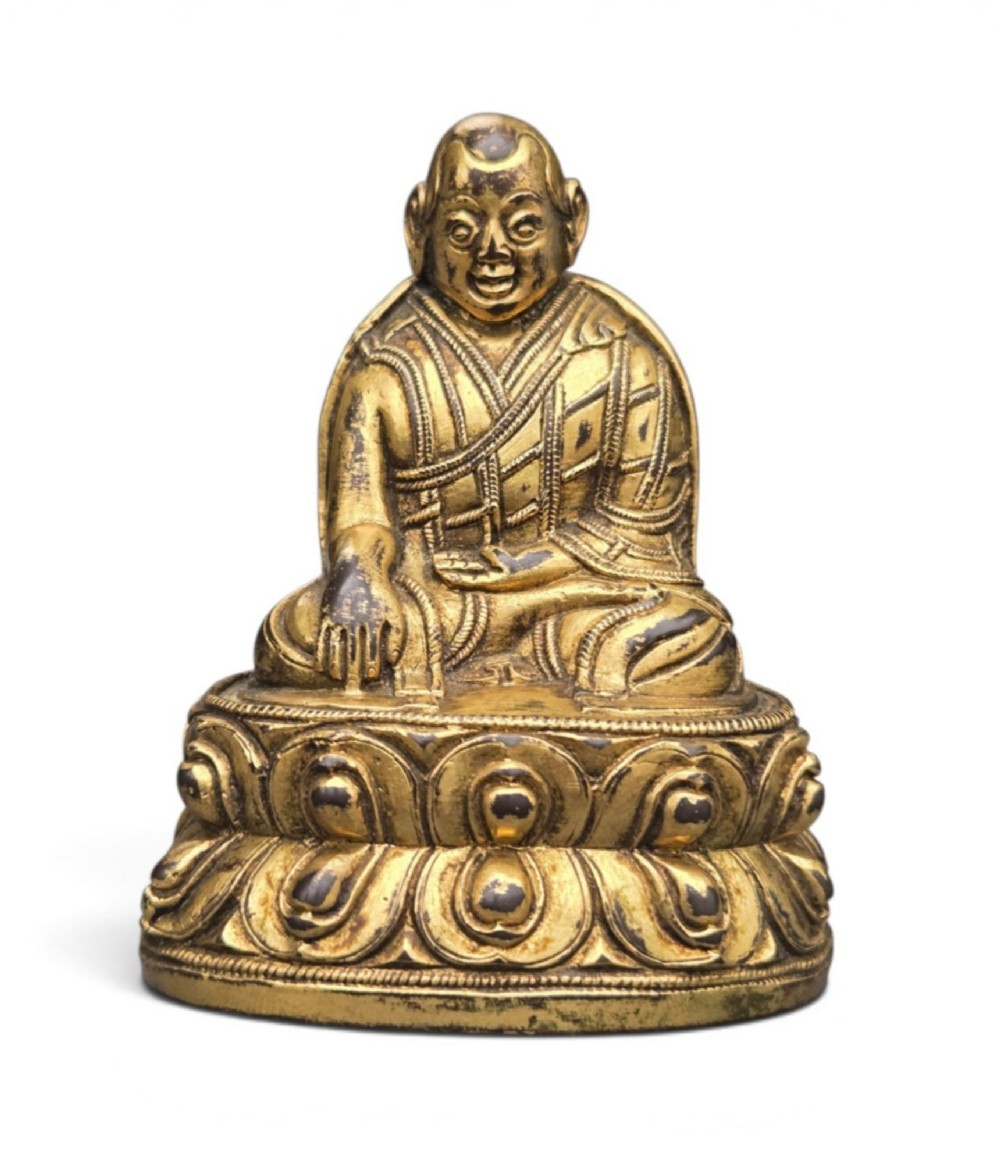 An 18th-century gilt-bronze miniature figure of Lama Shang seated cross-legged on a double-lotus pedestal in patterned robes.