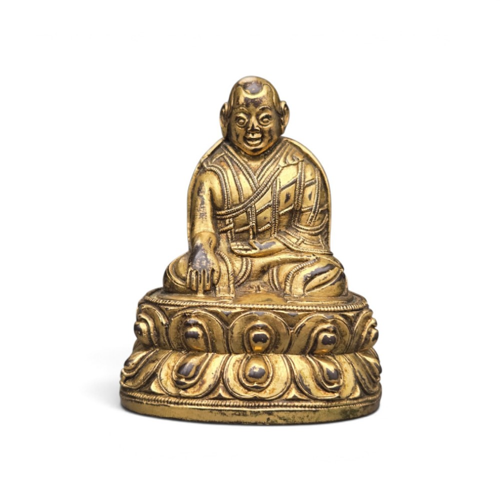 An 18th-century gilt-bronze miniature figure of Lama Shang seated cross-legged on a double-lotus pedestal in patterned robes. View XI