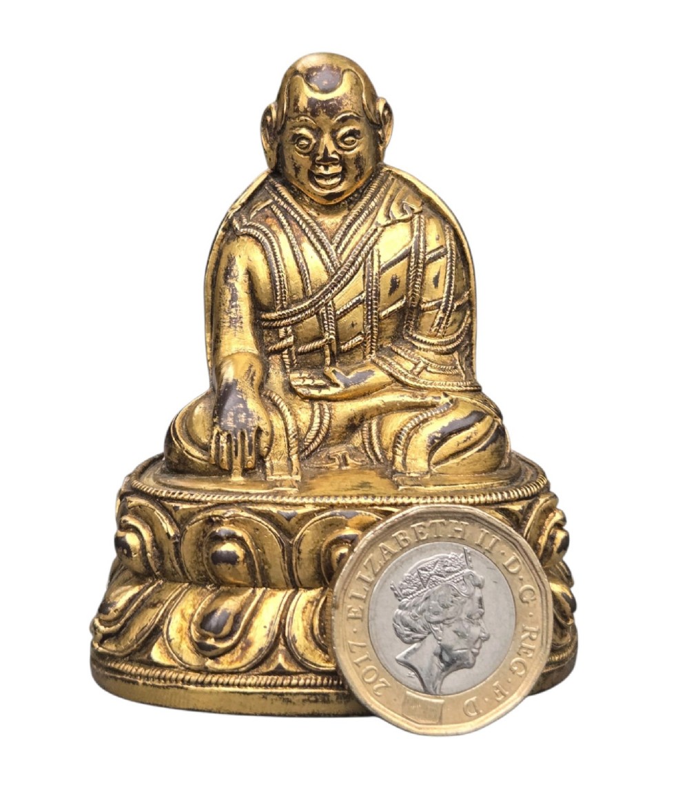 An 18th-century gilt-bronze miniature figure of Lama Shang seated cross-legged on a double-lotus pedestal in patterned robes. View XII