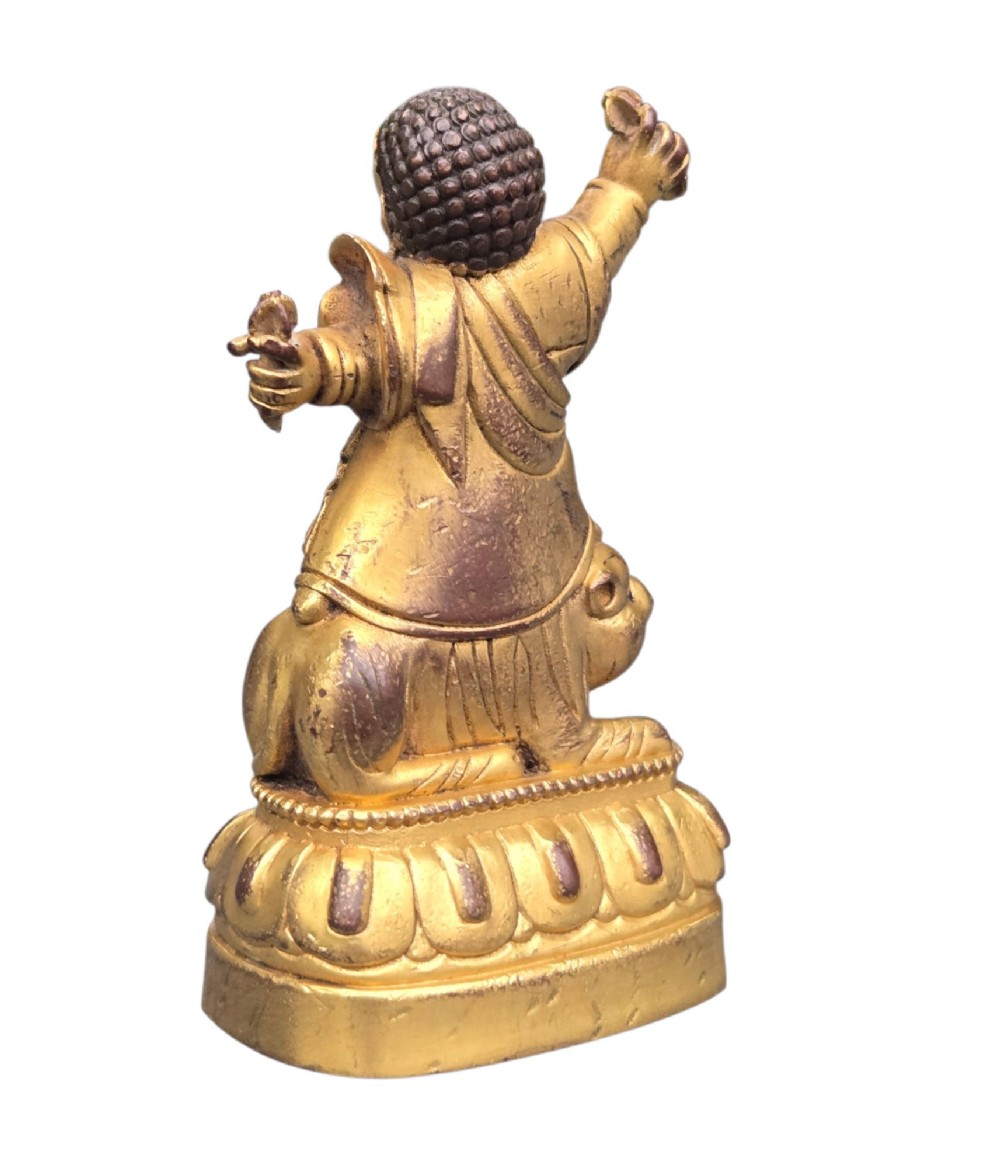 A sixteenth to seventeenth-century Sino-Tibetan gilt-bronze votive figure depicting a wrathful deity seated on a tiger atop a lotus pedestal. View IV