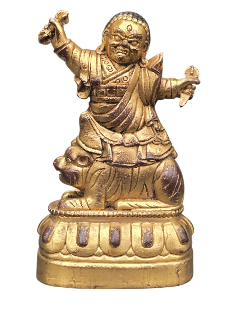 A sixteenth to seventeenth-century Sino-Tibetan gilt-bronze votive figure depicting a wrathful deity seated on a tiger atop a lotus pedestal. View VII