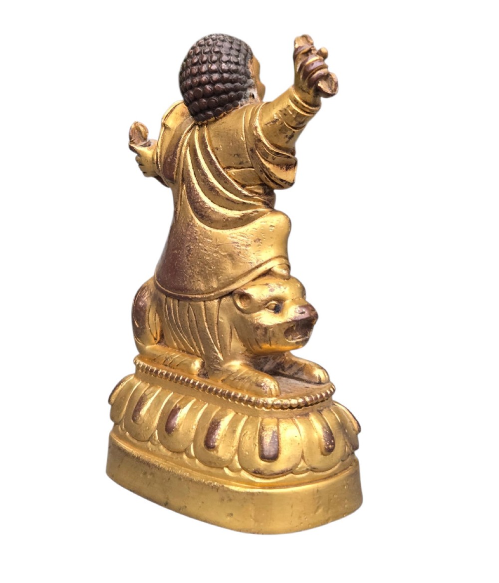 A sixteenth to seventeenth-century Sino-Tibetan gilt-bronze votive figure depicting a wrathful deity seated on a tiger atop a lotus pedestal. View XIII