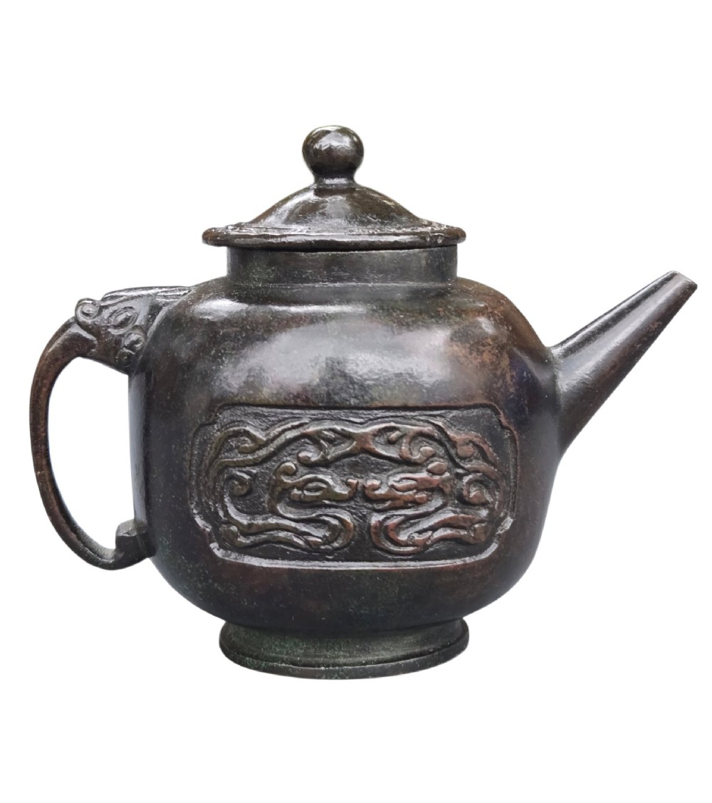 A dark patinated cast bronze vessel in ewer form featuring a dragon-head handle, a tapered spout, and carved relief panels. View IV