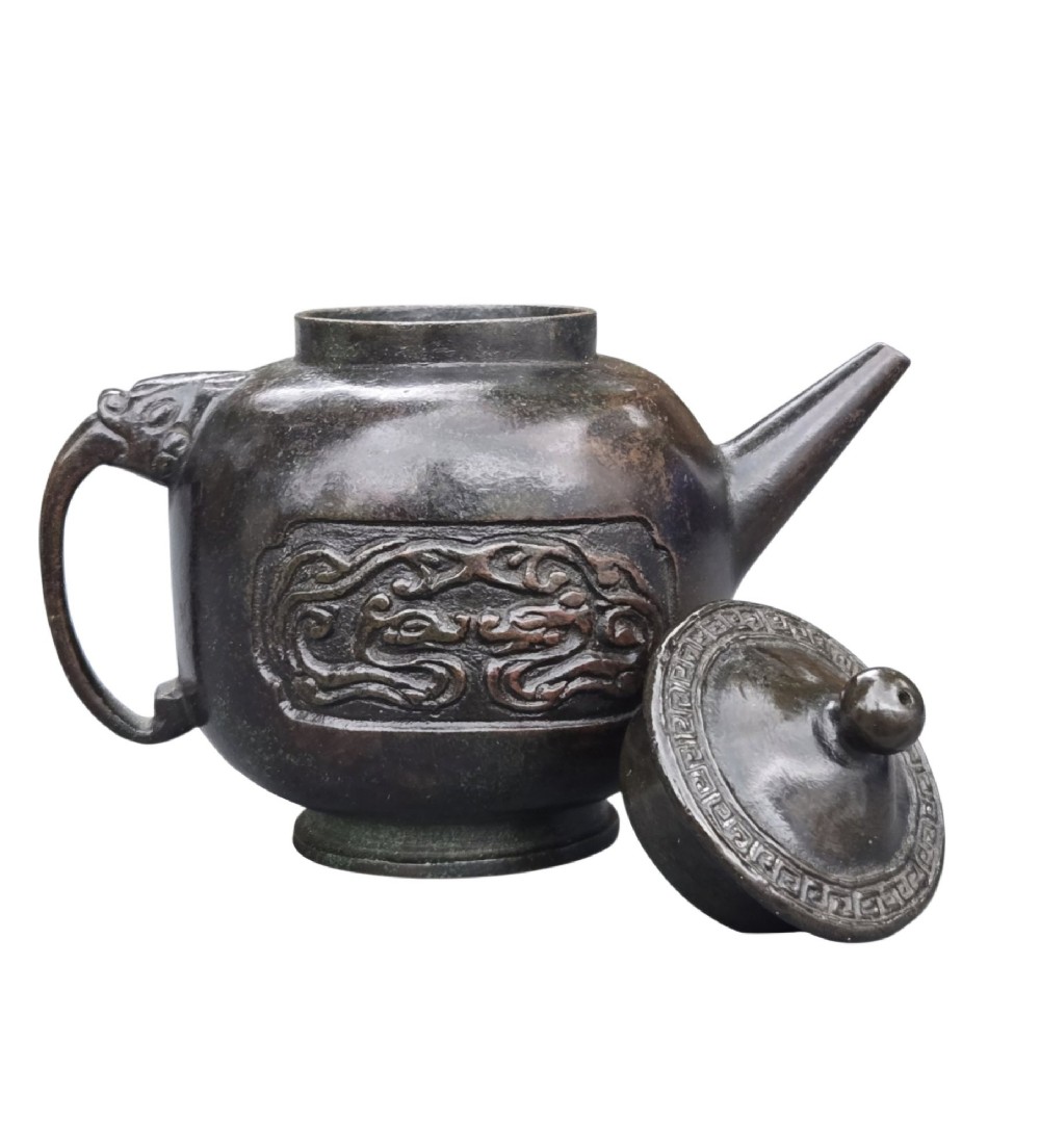 A dark patinated cast bronze vessel in ewer form featuring a dragon-head handle, a tapered spout, and carved relief panels. View V