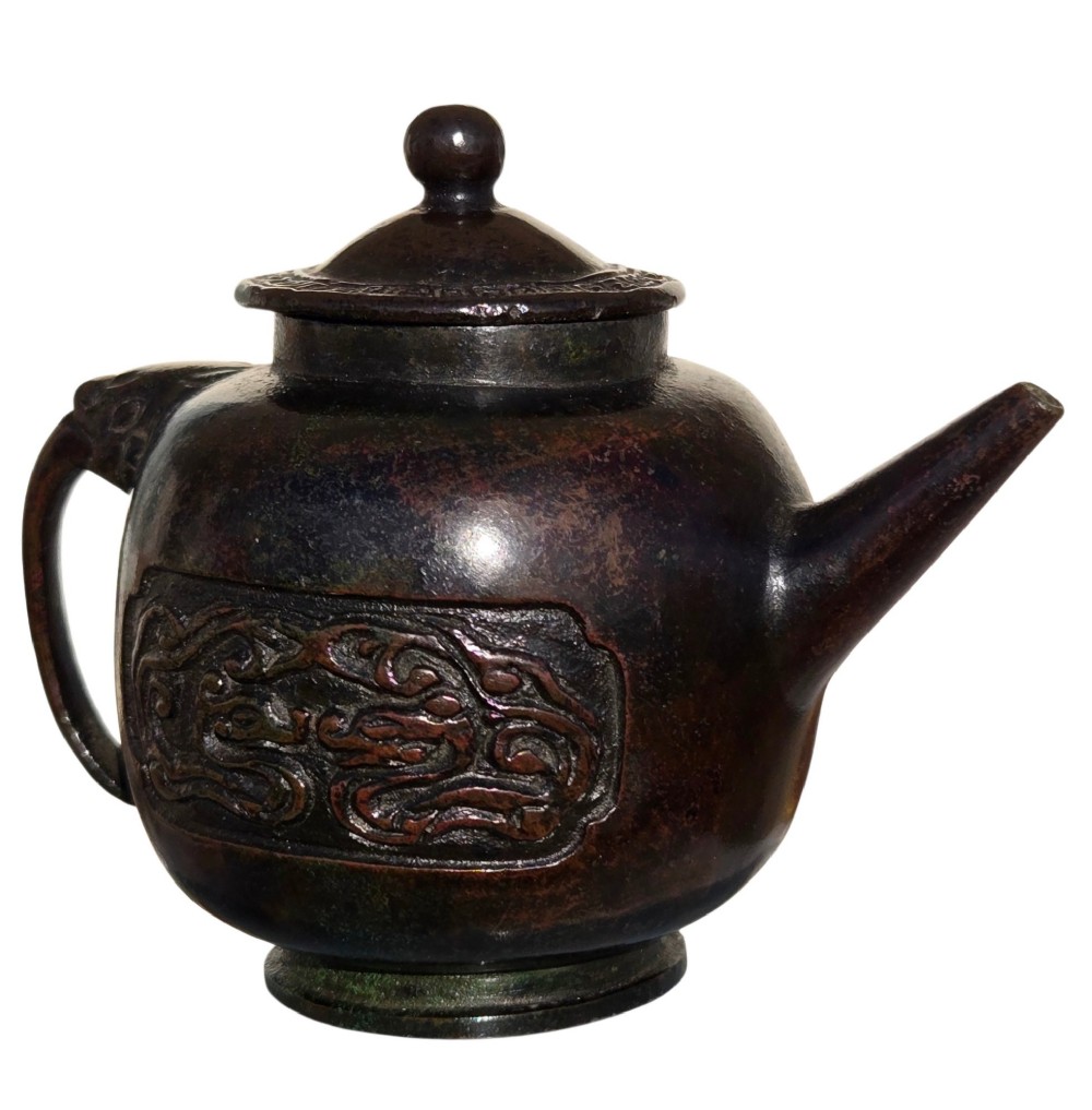 A dark patinated cast bronze vessel in ewer form featuring a dragon-head handle, a tapered spout, and carved relief panels. View VIII