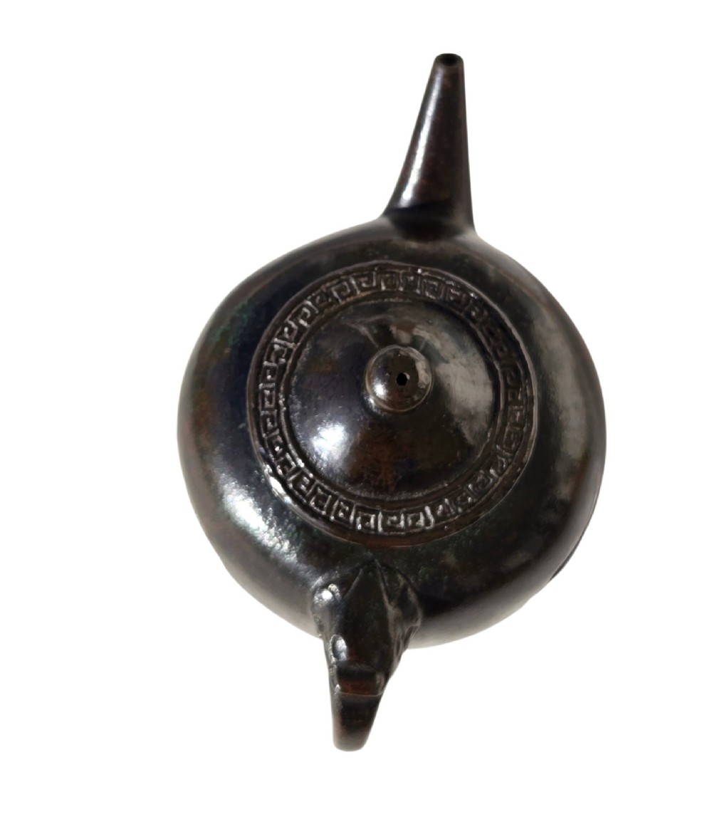 A dark patinated cast bronze vessel in ewer form featuring a dragon-head handle, a tapered spout, and carved relief panels. View XI