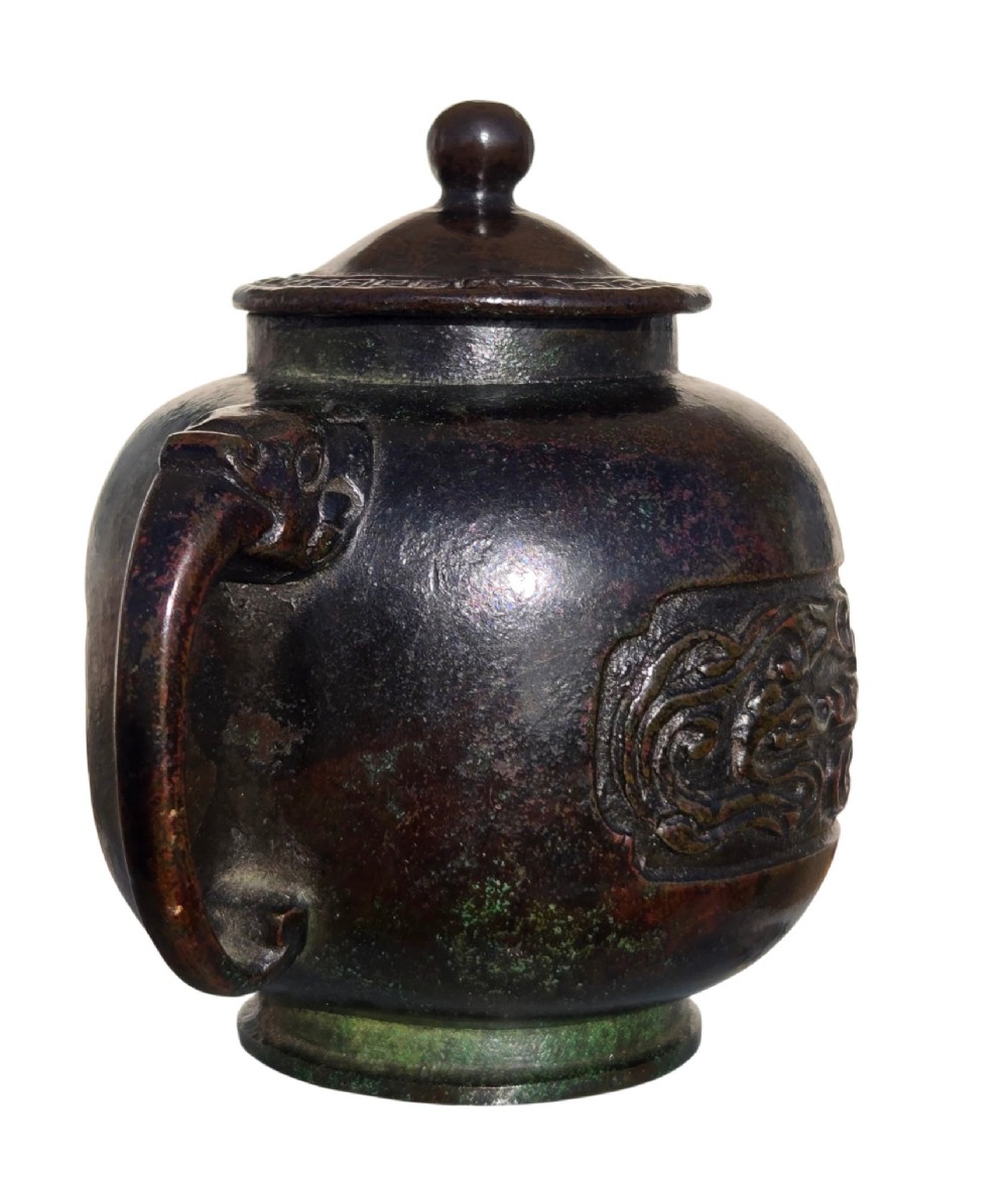A dark patinated cast bronze vessel in ewer form featuring a dragon-head handle, a tapered spout, and carved relief panels. View XII