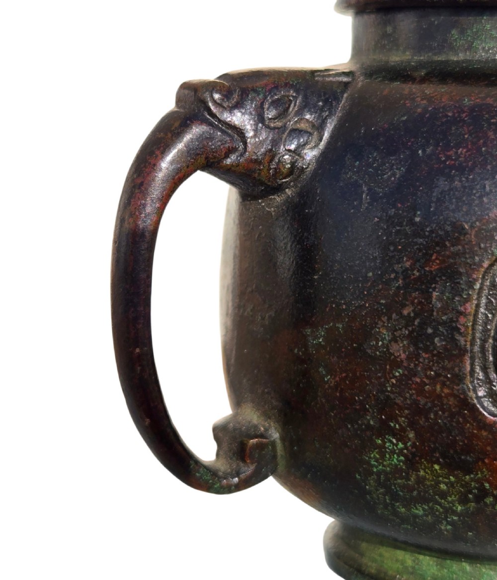 A dark patinated cast bronze vessel in ewer form featuring a dragon-head handle, a tapered spout, and carved relief panels. View XIII