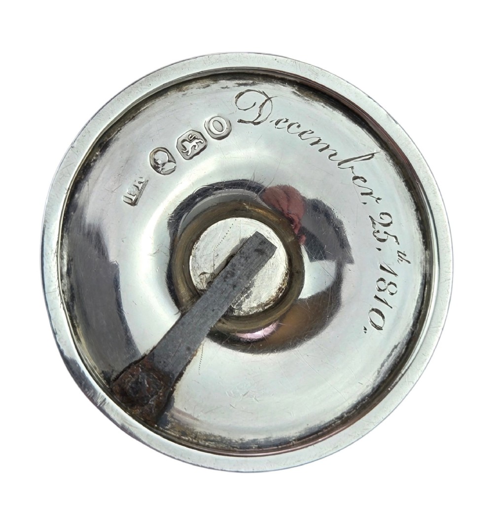 A small George III sterling silver taperstick featuring a flared sconce, a square central collar, a side ring handle, and a moulded circular base. View III