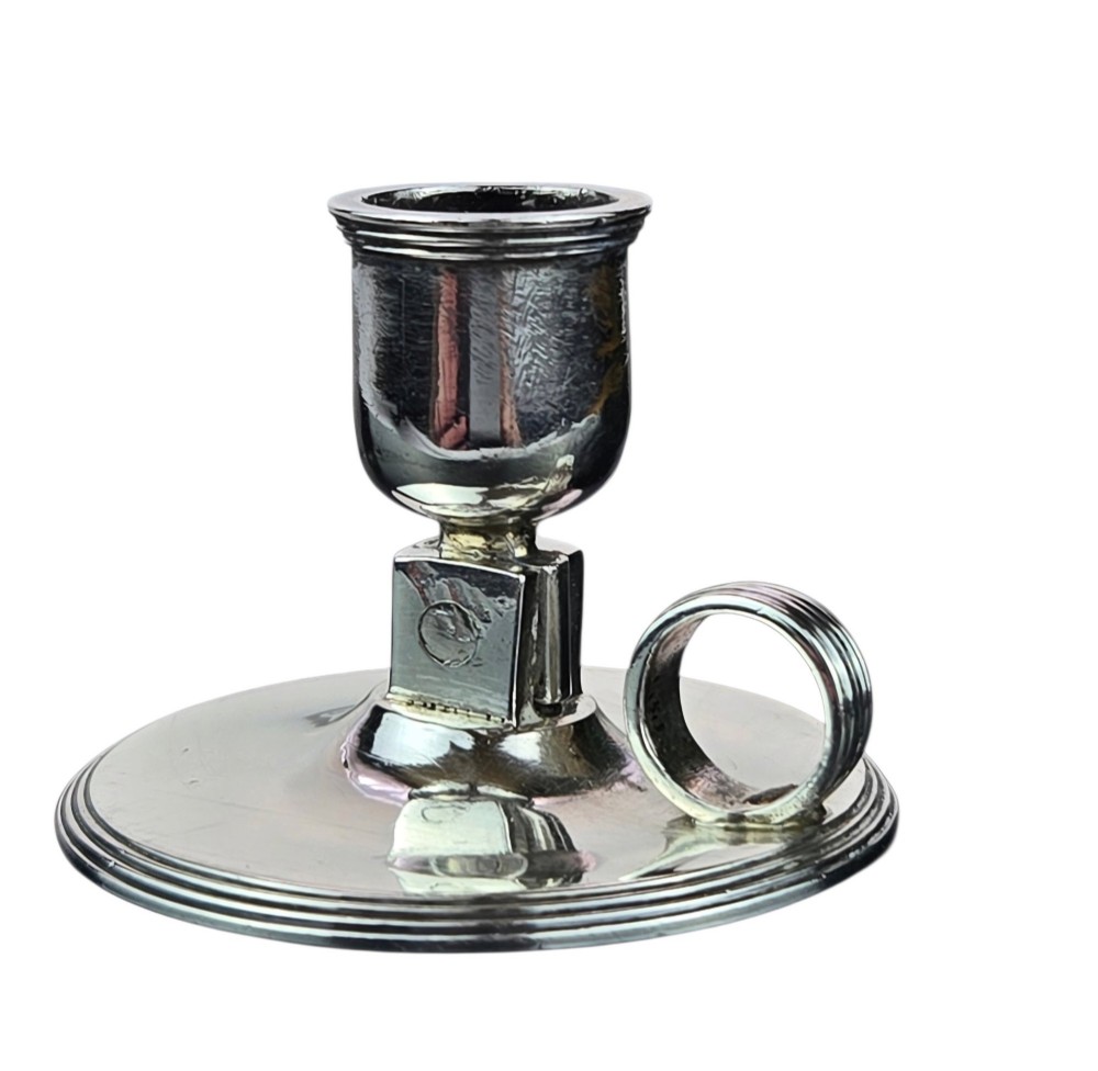 A small George III sterling silver taperstick featuring a flared sconce, a square central collar, a side ring handle, and a moulded circular base. View VIII