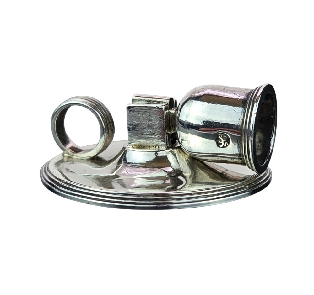 A small George III sterling silver taperstick featuring a flared sconce, a square central collar, a side ring handle, and a moulded circular base. View IX