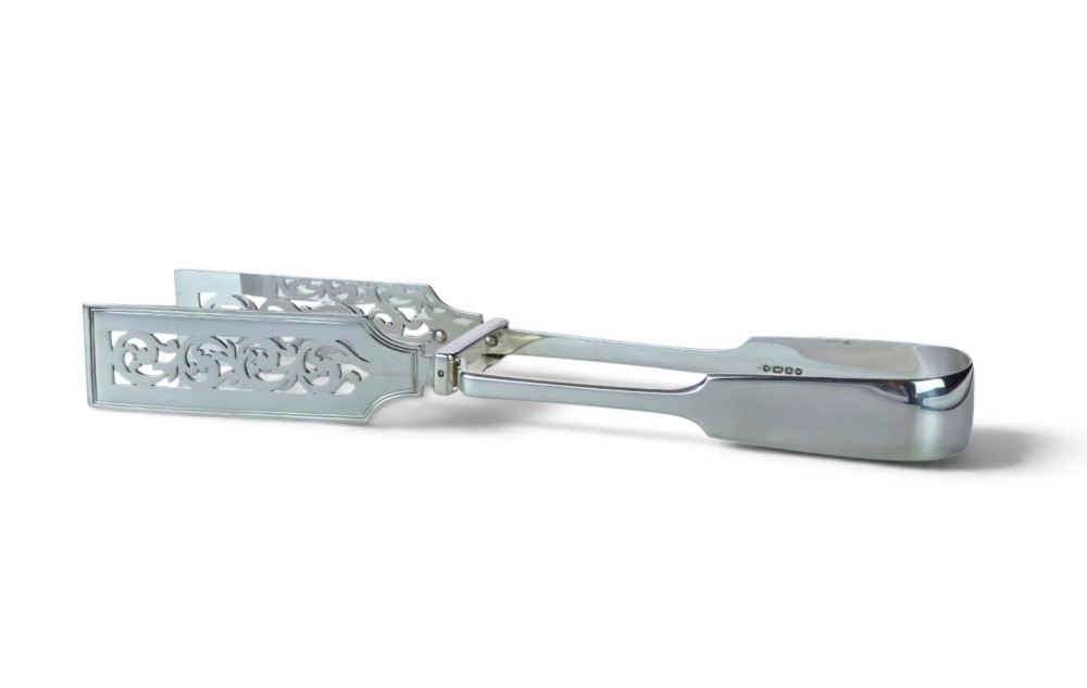 Victorian sterling silver asparagus tongs featuring wide, pierced scrollwork blades and clear assay hallmarks along the upper arm.