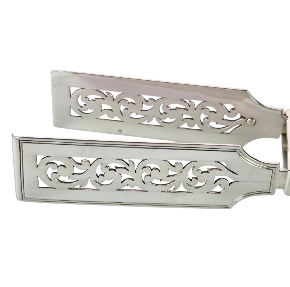 Victorian sterling silver asparagus tongs featuring wide, pierced scrollwork blades and clear assay hallmarks along the upper arm. View IX
