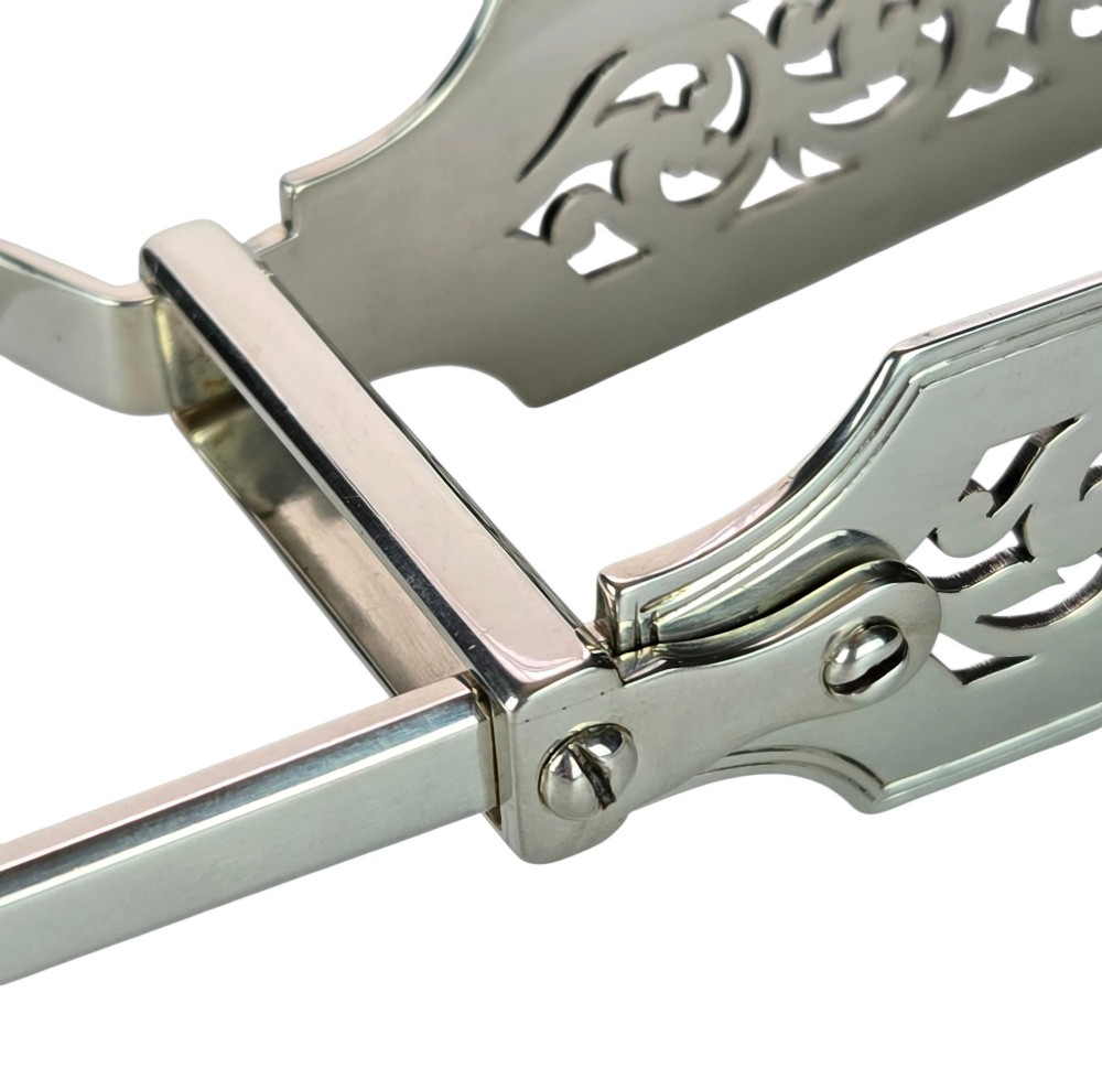 Victorian sterling silver asparagus tongs featuring wide, pierced scrollwork blades and clear assay hallmarks along the upper arm. View XI