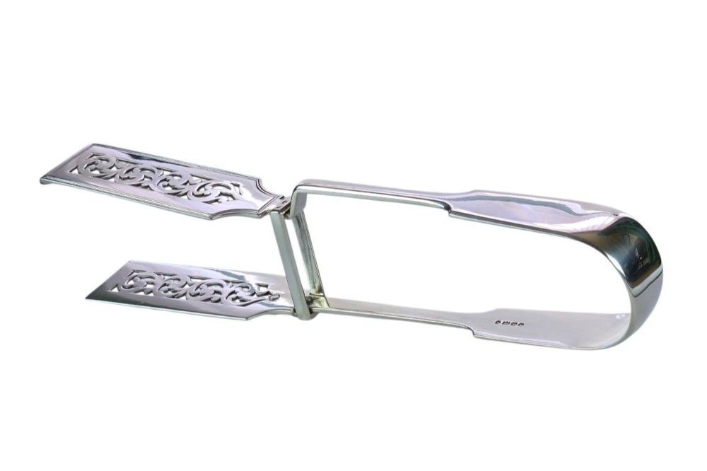 Victorian sterling silver asparagus tongs featuring wide, pierced scrollwork blades and clear assay hallmarks along the upper arm. View XV
