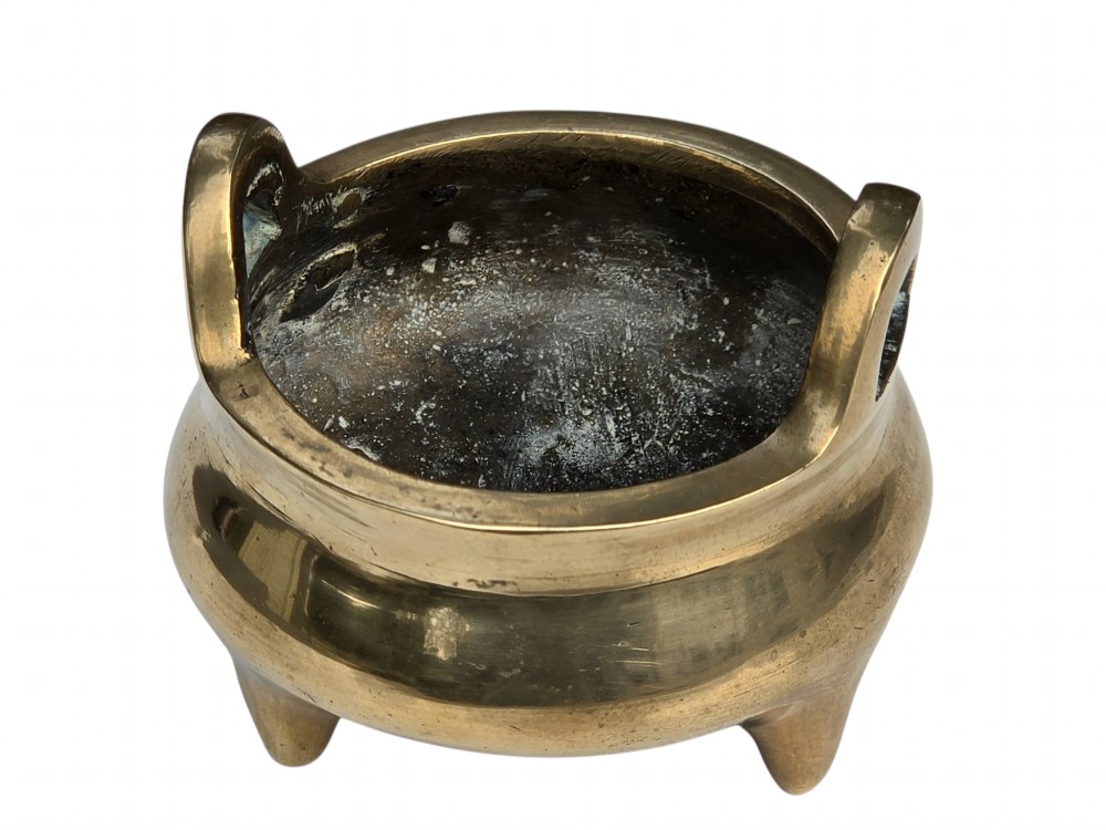A miniature cast bronze tripod censer featuring loop handles, conical legs, and natural surface patination. View V