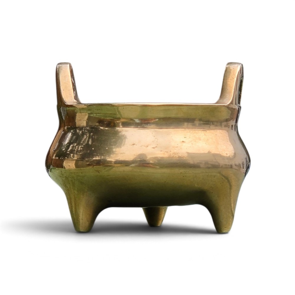 A miniature cast bronze tripod censer featuring loop handles, conical legs, and natural surface patination. View II