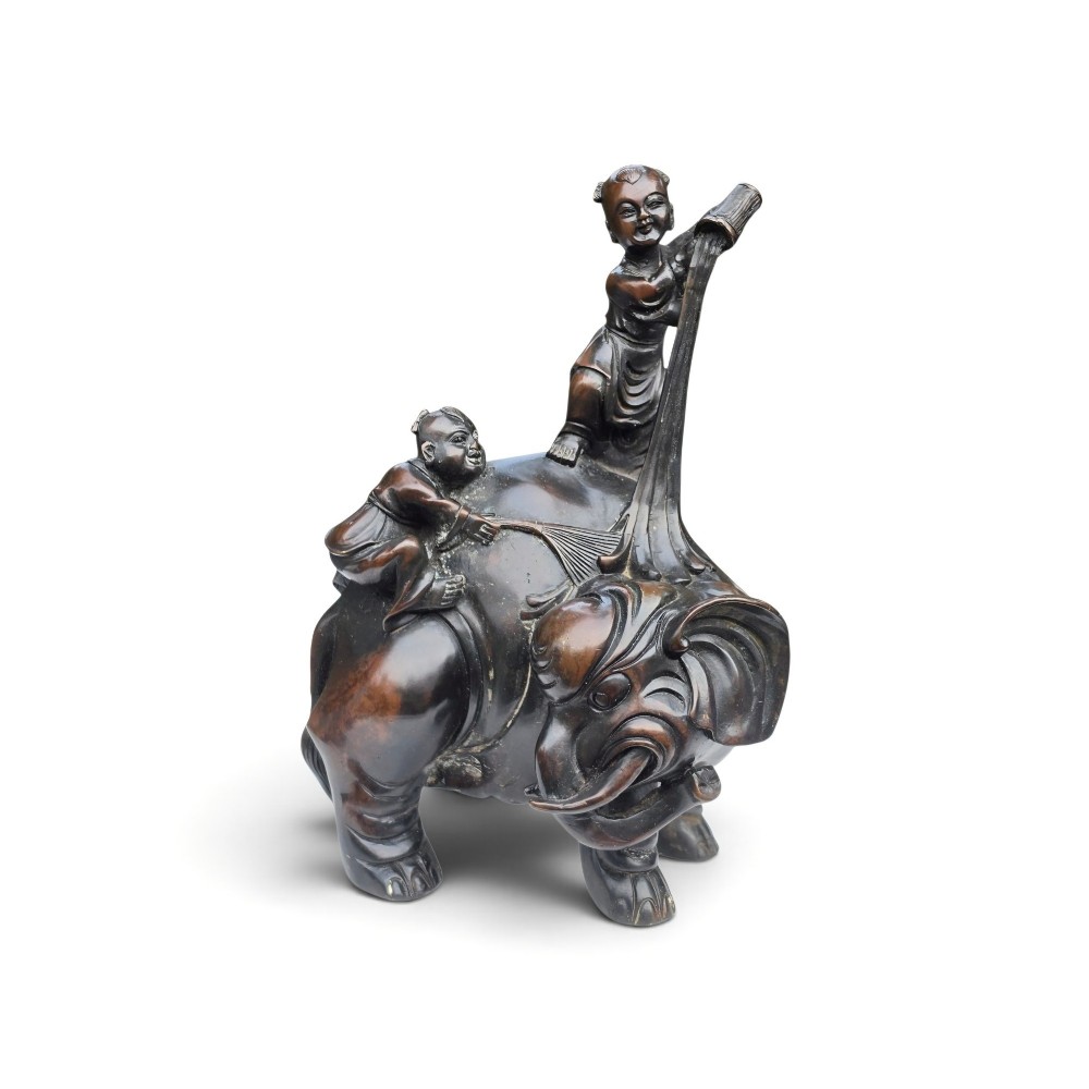 A dark patinated bronze Chinese sculpture depicting two young boys washing a caparisoned elephant.