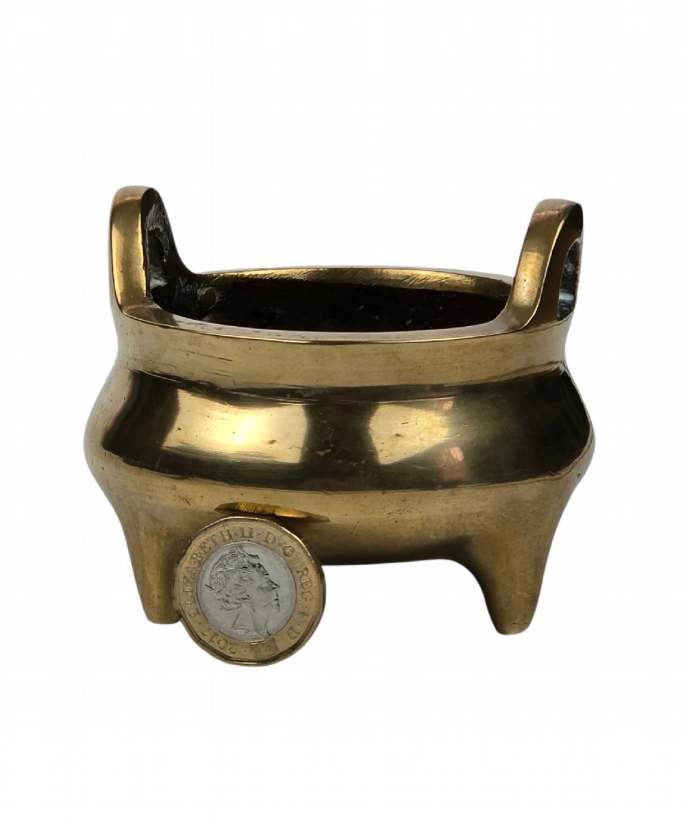A miniature cast bronze tripod censer featuring loop handles, conical legs, and natural surface patination. View VII