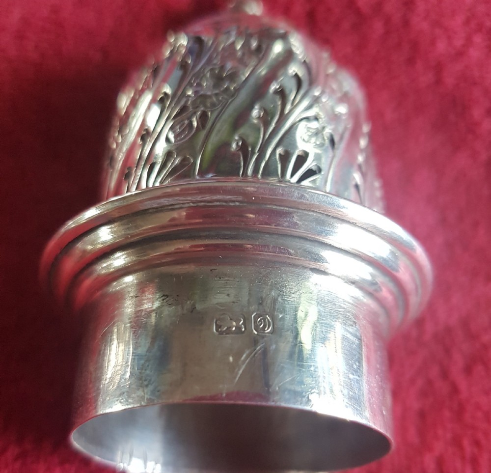 An ornate sterling silver sugar caster featuring intricate repousse floral motifs, a pierced decorative dome cover with a flame finial, and a fluted circular base. View IV