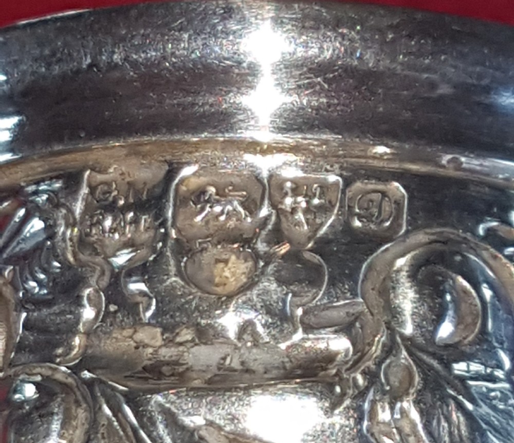 An ornate sterling silver sugar caster featuring intricate repousse floral motifs, a pierced decorative dome cover with a flame finial, and a fluted circular base. View V