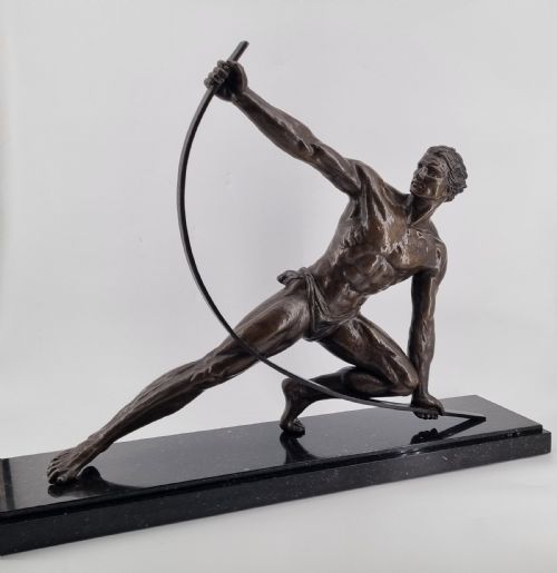 fig 3. An Art Deco dark bronze sculpture depicting a muscular male athlete bending an iron bar, mounted on a black marble plinth.