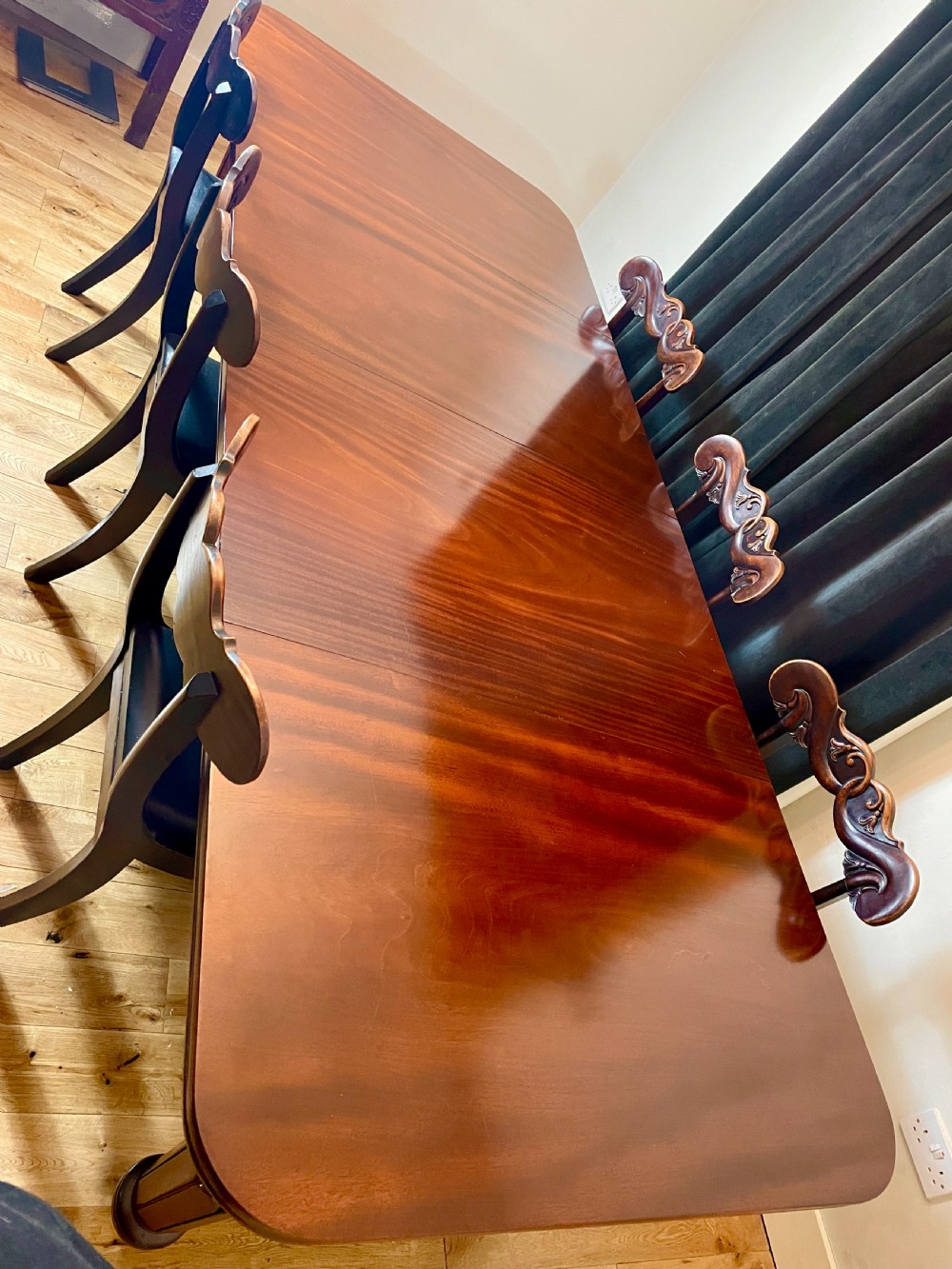 A William IV mahogany extending dining table with a polished surface, rounded corners, and turned reeded legs fitted with brass castors. View III