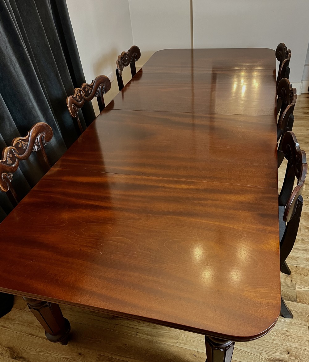 A William IV mahogany extending dining table with a polished surface, rounded corners, and turned reeded legs fitted with brass castors. View IV