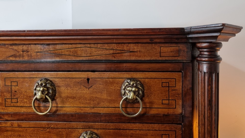 A 19th-century Regency mahogany chest on stand featuring fluted pilasters, lion mask brass ring handles, boxwood stringing, and reeded legs terminating in carved feet. View IX