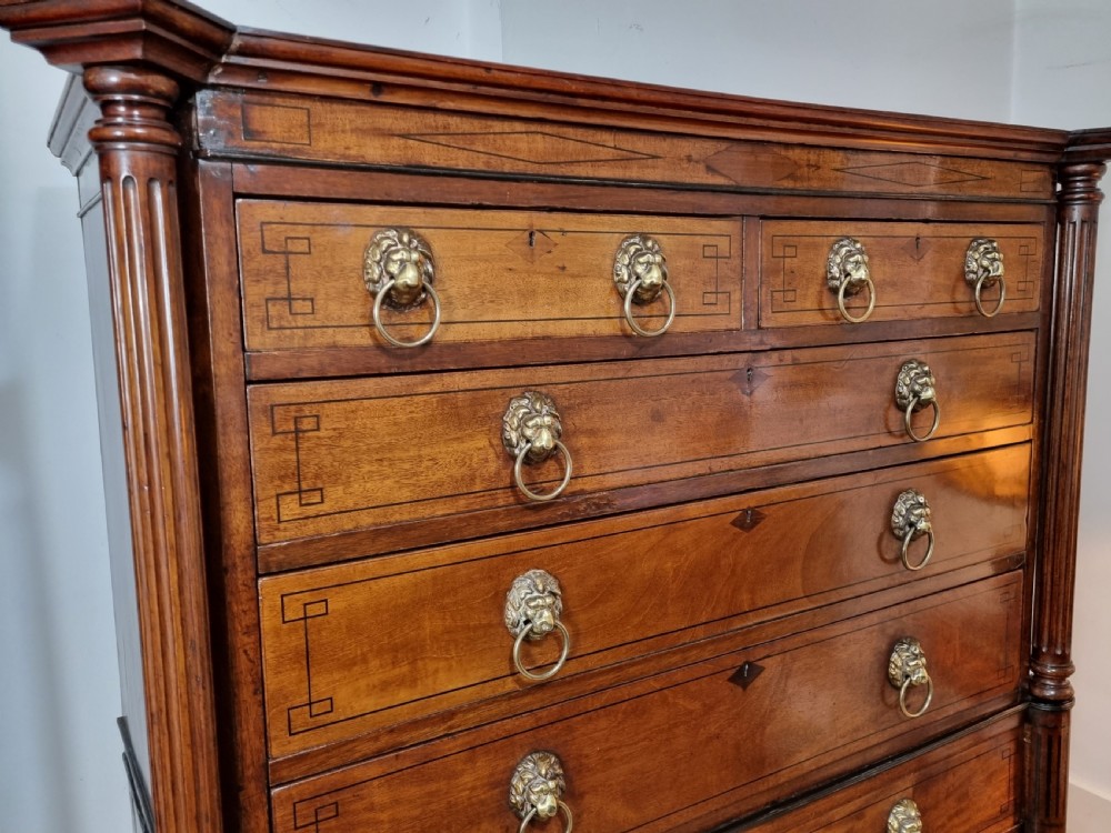 A 19th-century Regency mahogany chest on stand featuring fluted pilasters, lion mask brass ring handles, boxwood stringing, and reeded legs terminating in carved feet. View XI