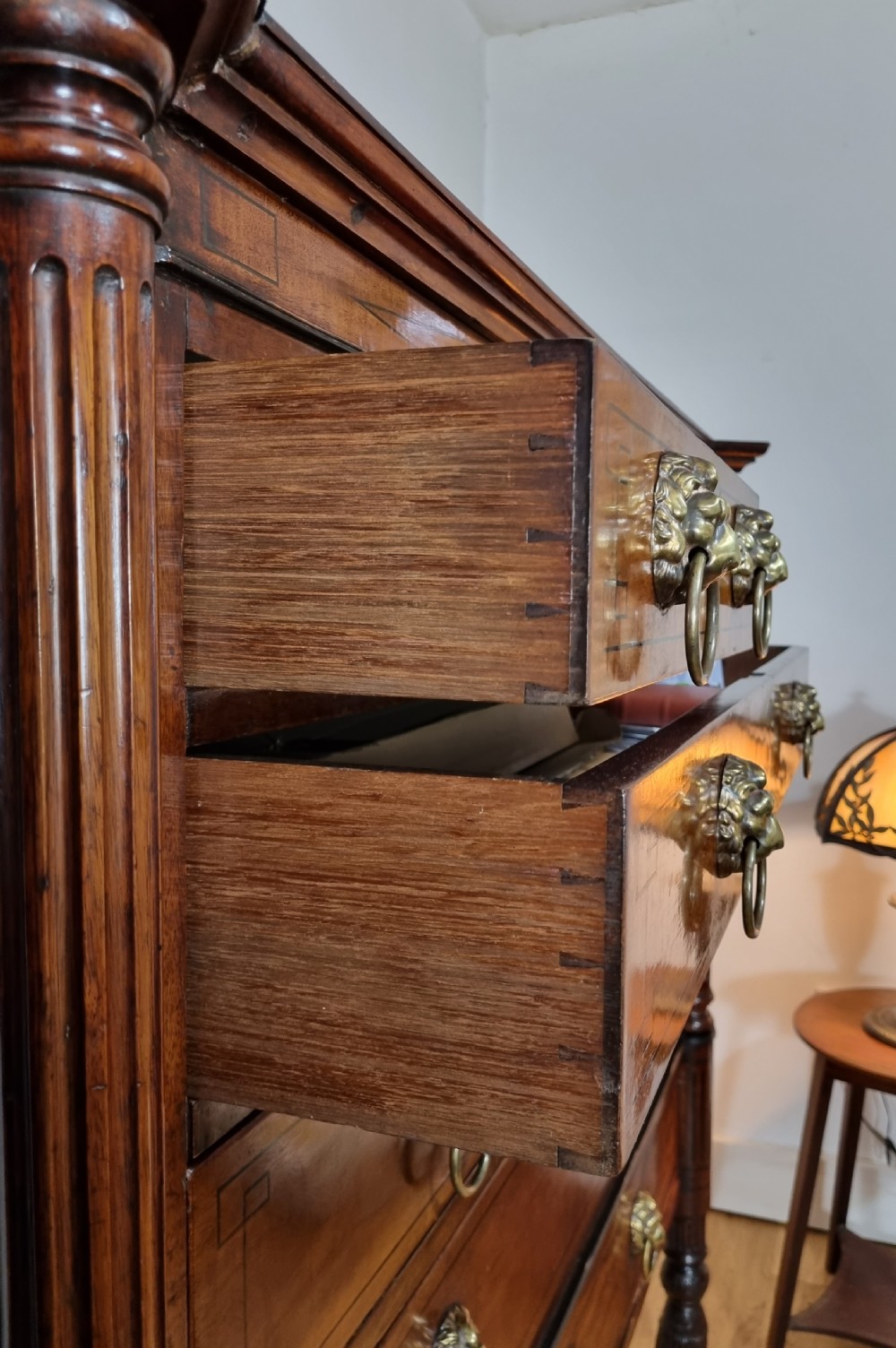 A 19th-century Regency mahogany chest on stand featuring fluted pilasters, lion mask brass ring handles, boxwood stringing, and reeded legs terminating in carved feet. View XII