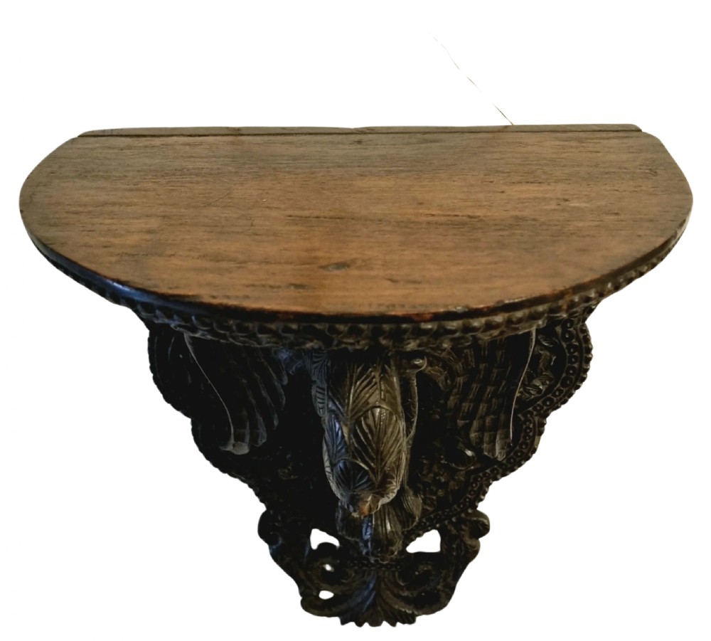 A 19th-century dark carved teak wall bracket featuring an undercut bird support figure and intricate foliate tracery. View II
