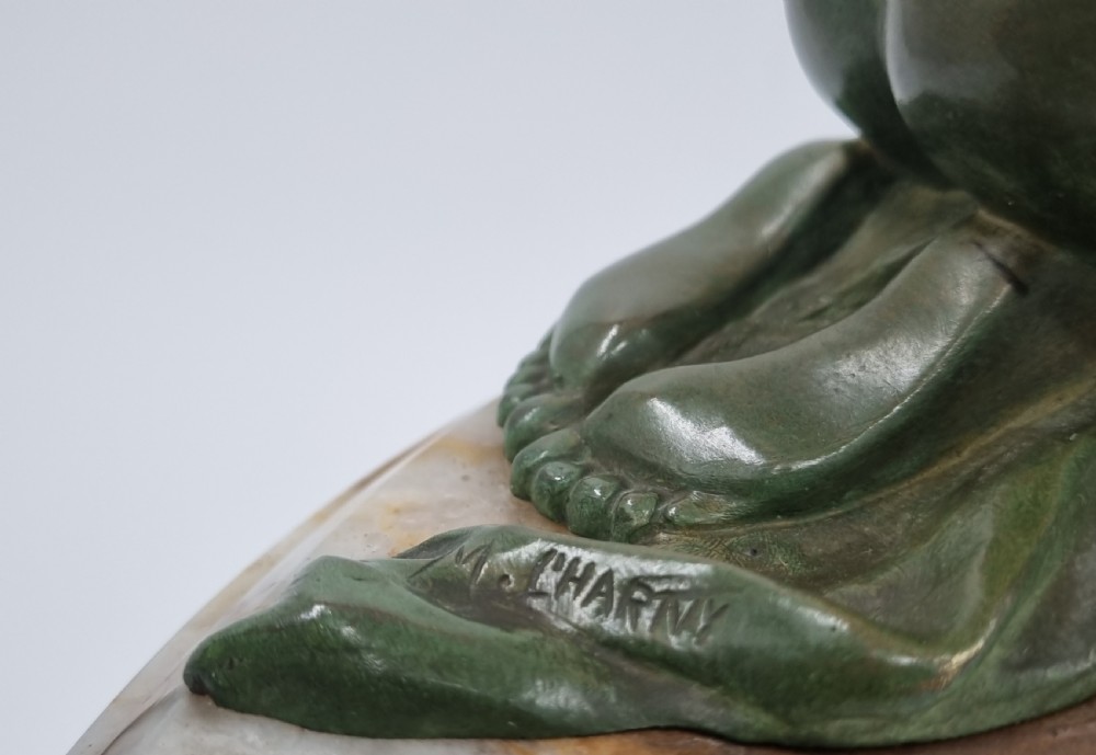 An Art Deco clock garniture set featuring a carved onyx mantel clock topped with a green patinated bronze sculpture of a kneeling woman, accompanied by two matching onyx cups. View V
