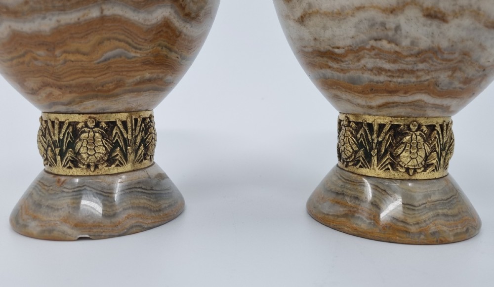 An Art Deco clock garniture set featuring a carved onyx mantel clock topped with a green patinated bronze sculpture of a kneeling woman, accompanied by two matching onyx cups. View VII