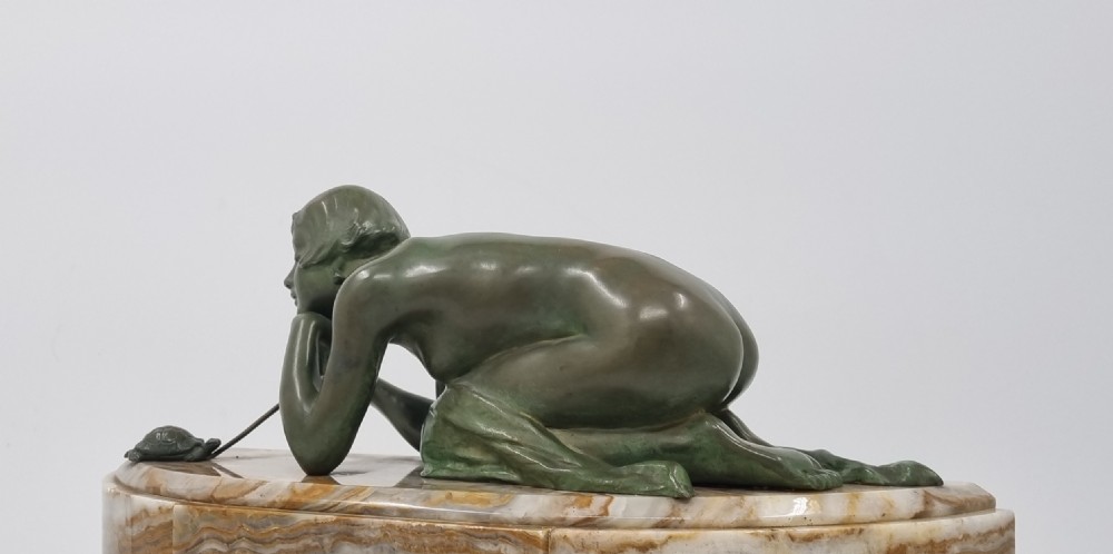 An Art Deco clock garniture set featuring a carved onyx mantel clock topped with a green patinated bronze sculpture of a kneeling woman, accompanied by two matching onyx cups. View XII