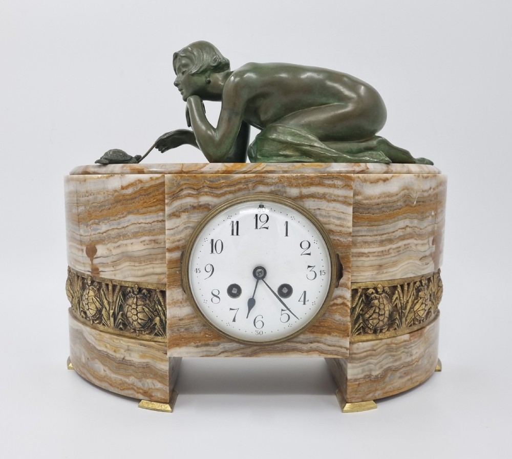 An Art Deco clock garniture set featuring a carved onyx mantel clock topped with a green patinated bronze sculpture of a kneeling woman, accompanied by two matching onyx cups. View XIV