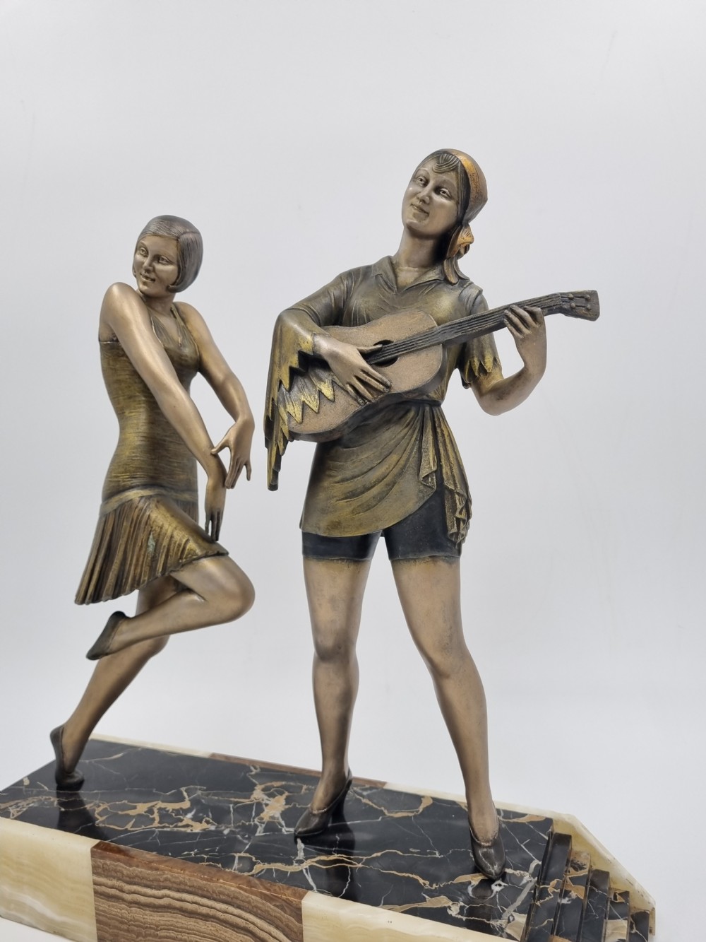 An Art Deco bronze sculpture featuring a dancing woman and a musician playing a stringed instrument set upon a layered onyx and marble plinth base. View V