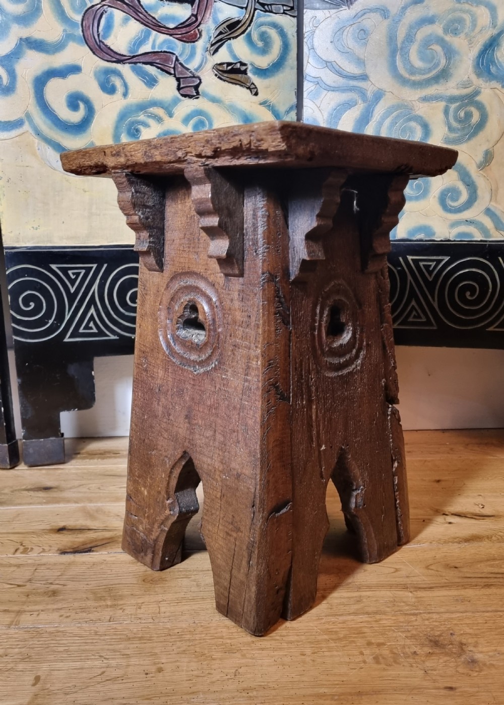A 19th-century carved dark oak Gothic Revival stool featuring arch cutouts, carved circular motifs, and bracketed top supports. View VI