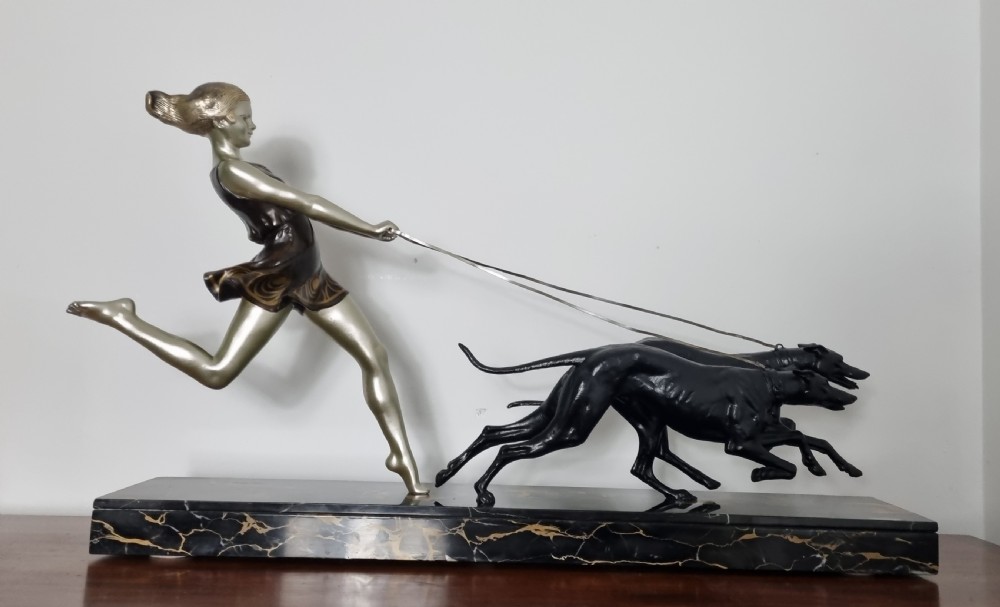 An Art Deco sculpture depicting a silvered female figure running alongside two dark greyhounds, mounted on a black marble base. View XVII