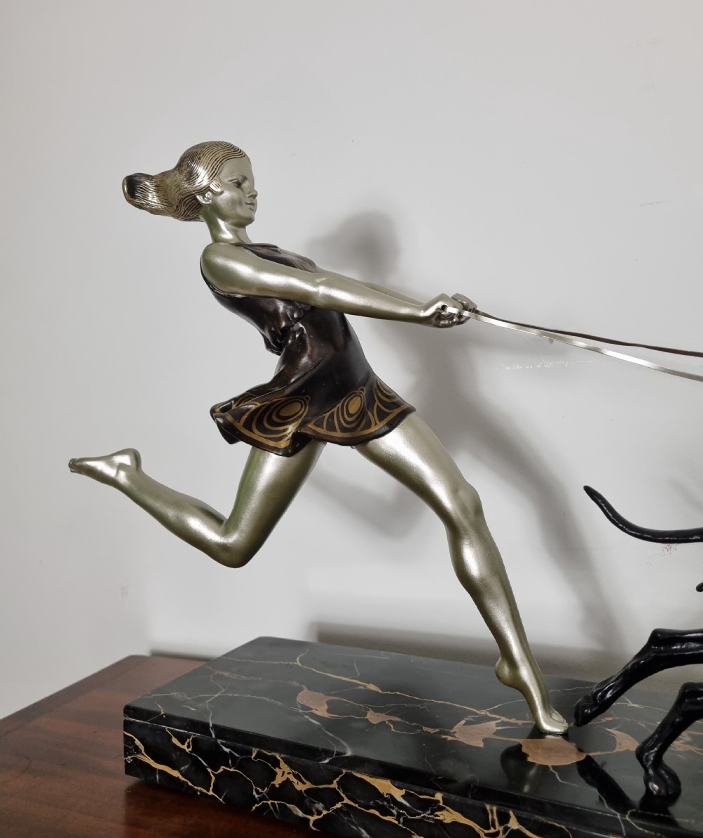 An Art Deco sculpture depicting a silvered female figure running alongside two dark greyhounds, mounted on a black marble base. View II